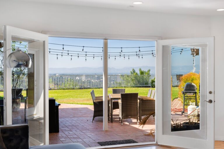 Living room with open patio door and large glass doors in Hidden Hills, CA